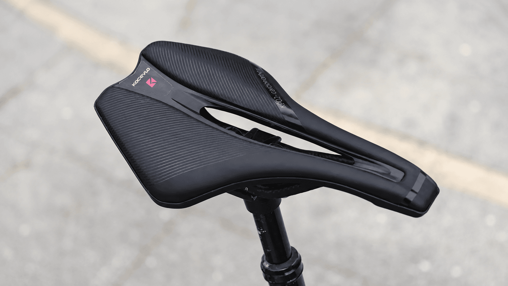 Outdoor real shot of KOCEVLO KP02 carbon bicycle saddle mounted on road bike seat post, pavement installation display